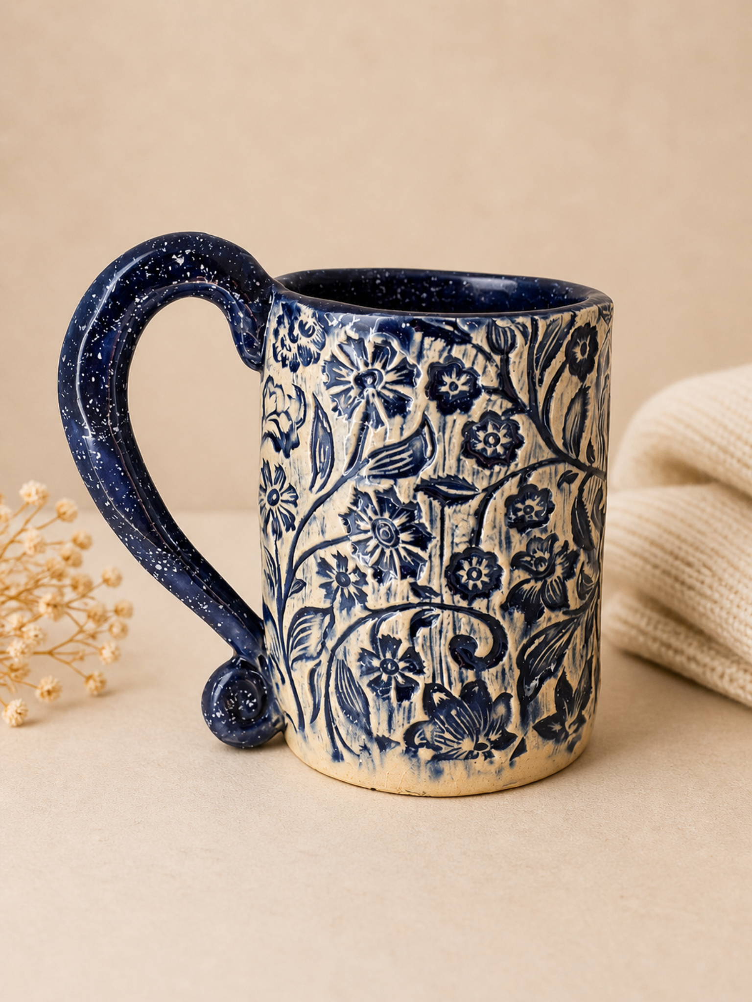 Blauer Keramikbecher mit floralem Muster und geschwungenem Henkel handgefertigt