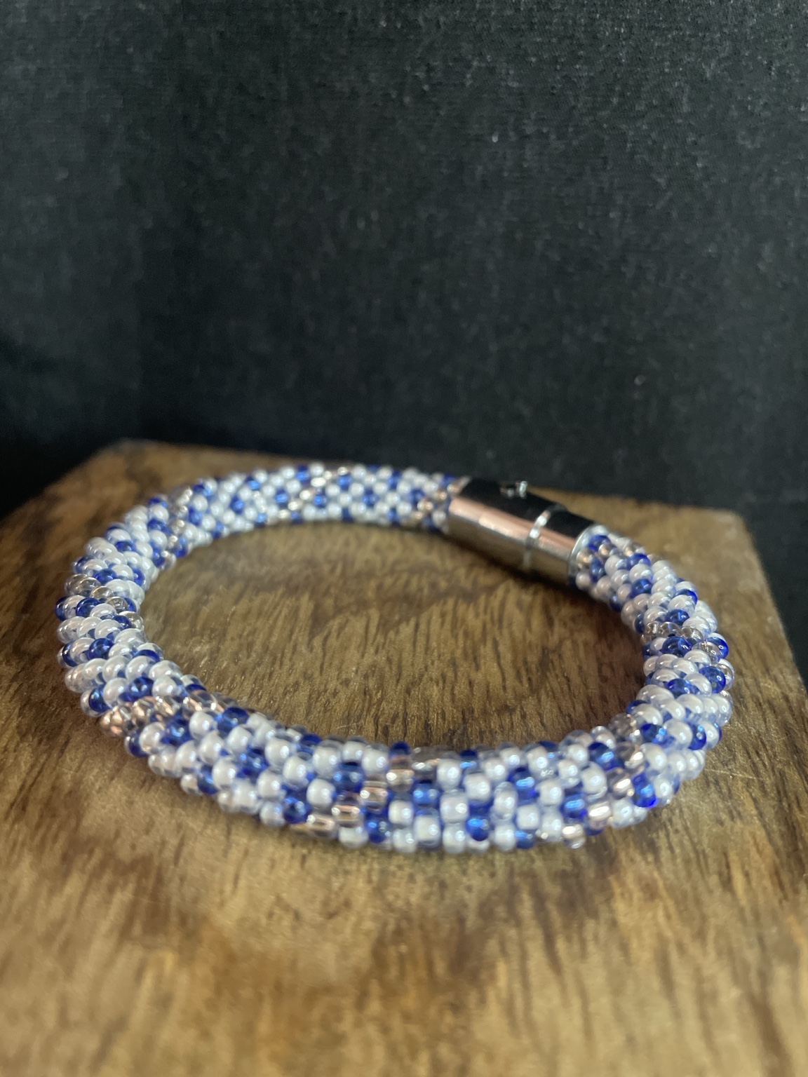 Handgefertigtes Glasperlenarmband in Royalblau und Weiß mit Magnetverschluss auf schwarzem Hintergrund