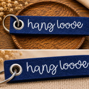 Dunkelblauer Filz-Schlüsselanhänger mit hang loose Schriftzug auf dekorativer Holzschale