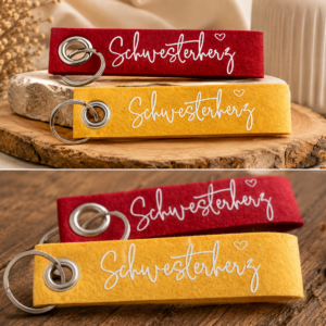 Filz-Schlüsselanhänger mit Schriftzug Schwesterherz und Metallring in Rot auf Holzuntergrund