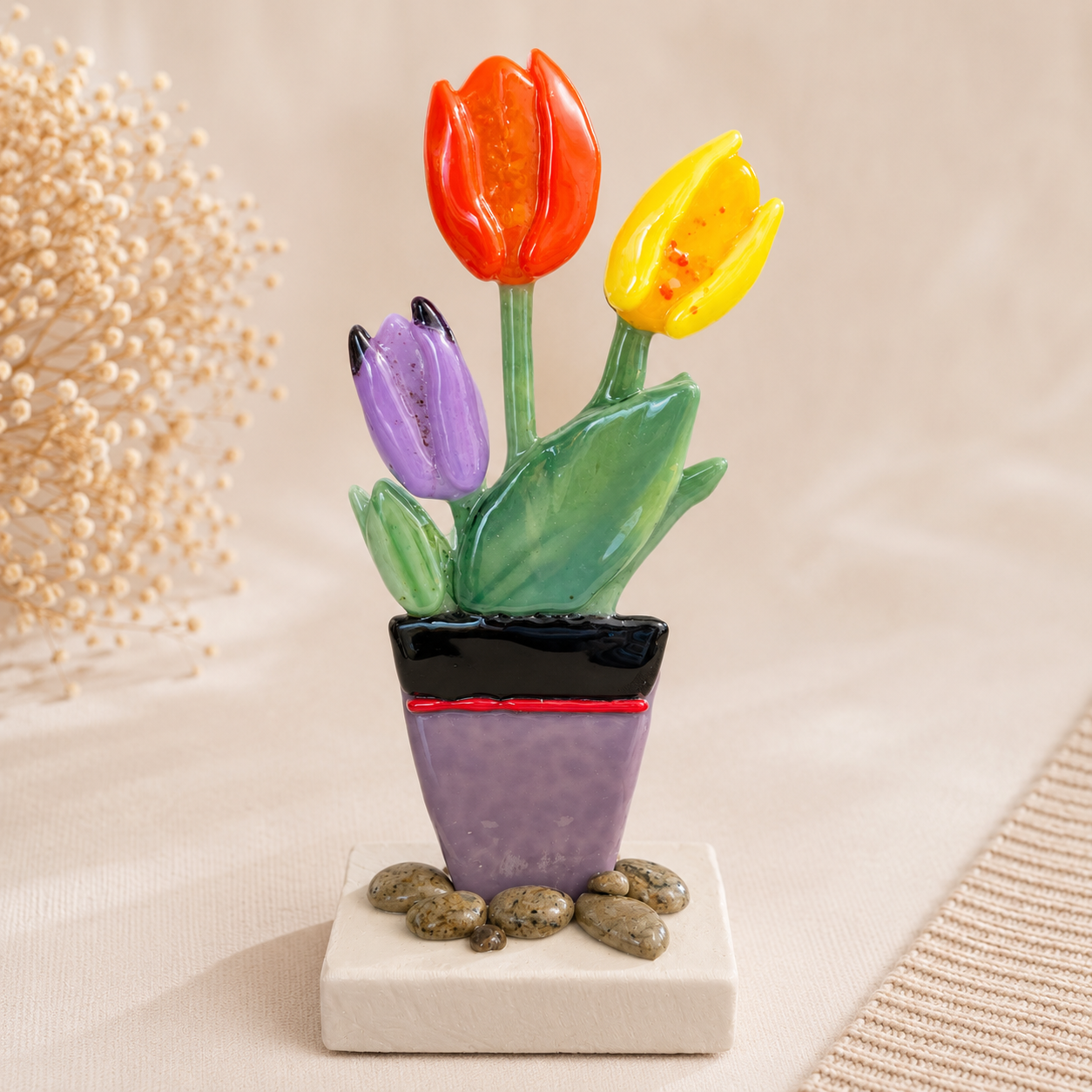 Bunte handgefertigte Glas-Tulpen im dekorativen Blumentopf auf hellem Hintergrund