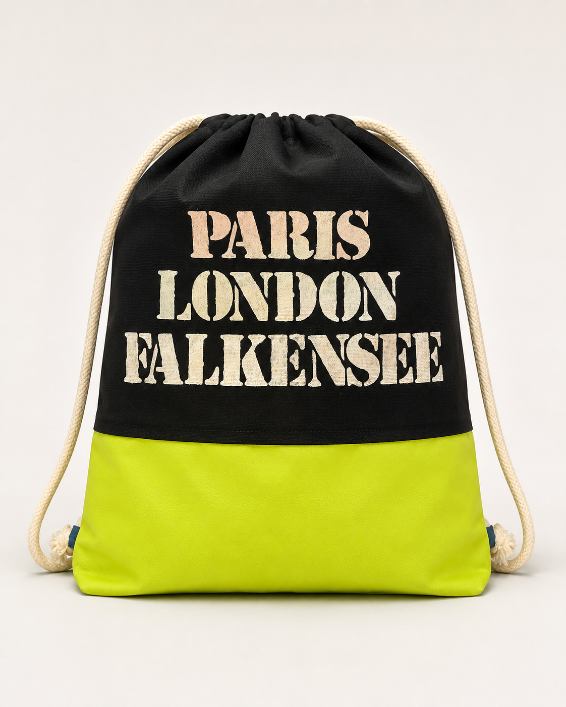Handgefertigter Turnbeutel aus schwarzem Stoff mit neongelbem Unterteil und dem Aufdruck „Paris London Falkensee“.