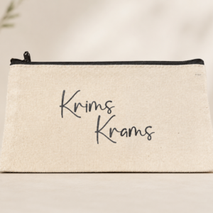 Naturfarbene Kosmetiktasche mit schwarzem Reißverschluss und Aufdruck „Krims Krams“ auf hellem Hintergrund.