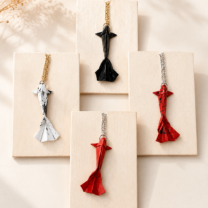 Handgefertigte Origami Koi Halsketten in verschiedenen Farben auf hellen Schmuckkarten präsentiert. Japanisch inspirierter Schmuck mit Koi-Anhänger.