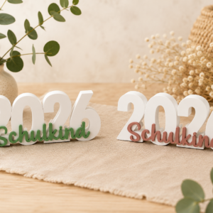 Zwei 3D-gedruckte Tischaufsteller mit der weißen Jahreszahl 2026 und dem Schriftzug Schulkind in Grün und Rosa.