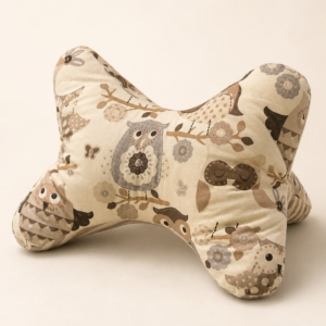 Leseknochen aus hellem Stoff mit Eulen, Blumen und Zweigen in Beige-, Braun- und Grautönen.
