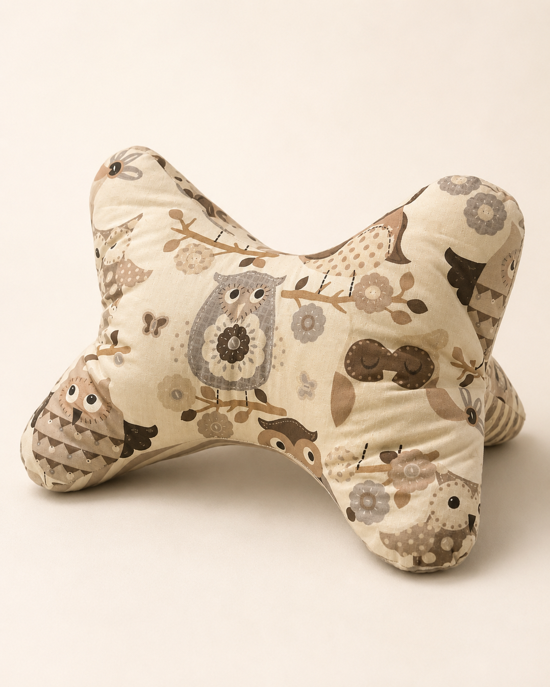 Leseknochen aus hellem Stoff mit Eulen, Blumen und Zweigen in Beige-, Braun- und Grautönen.